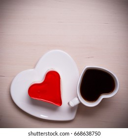Heart shaped coffee cup and jelly cake on wooden surface, top view copy space for text