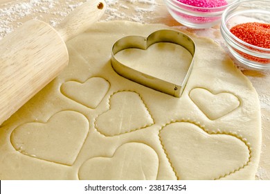 Heart Shaped Cookie Cutters Cutting Out Holiday Sugar Cookies With Wooden Rolling Pin And Red And Pink Sugar Sprinkles