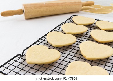 Heart shaped cookies on a cooling rack with a rolling pin and dough in the background. - Powered by Shutterstock