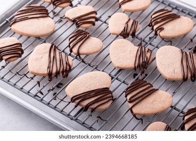 Heart shaped cookies with strawberry flavor, drizzled with dark chocolate on a cooling rack - Powered by Shutterstock