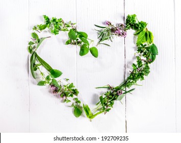 Heart shaped frame of assorted sprigs of fresh green culinary herbs arranged on a rustic white wooden background symbolic of love and romance with central copyspace - Powered by Shutterstock