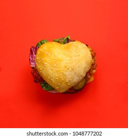 Herzförmiger Hamburger, Liebhaber-Burger-Fast-Food-Konzept auf rotem Hintergrund, Draufsicht