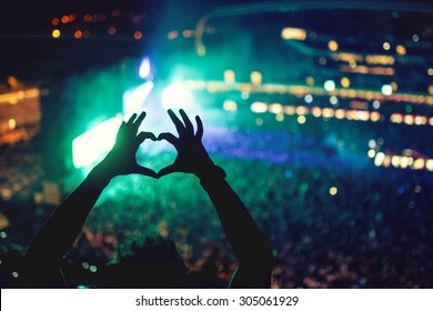 Heart Shaped Hands At Concert, Loving The Artist And The Festival. Music Concert With Lights And Silhouette Of A Man Enjoying The Concert