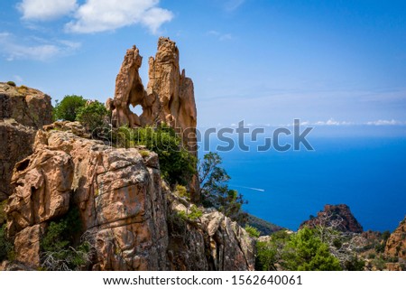 Heart shaped hole in a red rock, with  blue sky and sea as a background, Heart of Calanches de Piana, Corsica