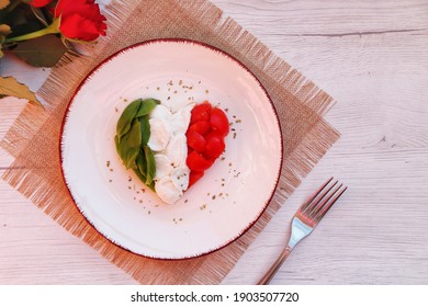 
Heart shaped Italian Caprese Salad arranged by Italian basil,buffalo mozzarella and tomatoes look like Italian Flag on plate with white wood table background.Love Italian food concept for Valentine