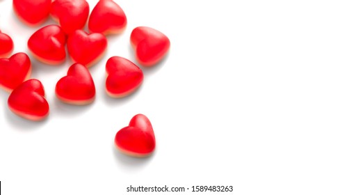 Heart shaped jelly candy, love background. Red jelly sweets candies on white backdrop. St. Valentines, marriage hearts border background. Closeup