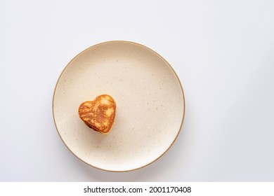 Heart Shaped Pancake On Beige Plate Over White Background. Top View.