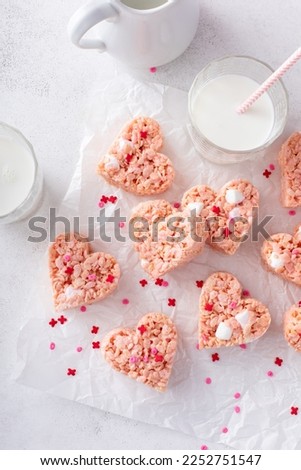 Heart shaped pink rice krispie treats for Valentines Day with red heart sprinkles served with milk