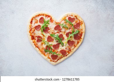 Heart shaped pizza with pepperoni. Valentines day romantic menu concept for restaurant or delivery.