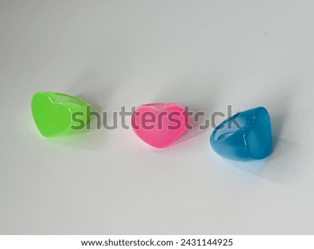 A heart shaped plastic resin ring in pink, blue, and green colors, with a white background Stock foto © 