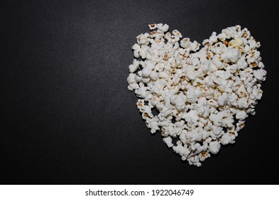 Heart shaped popcorn on black background with place for text.