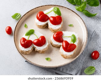 Heart shaped sandwiches with cherry hearts made of tomatoes, basil leaves and cream cheese spread. Saint Valentine's day breakfast. Festive vegetarian food. Love day food. Close up view. - Powered by Shutterstock