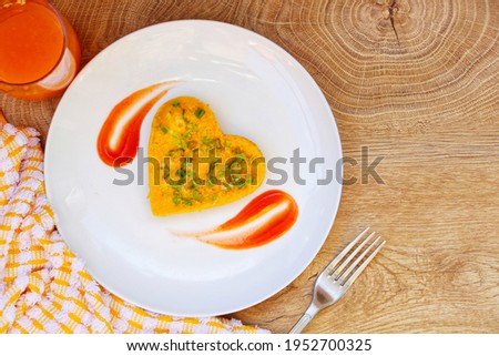 Heart shaped spring onions and cheeses omelette served with ketchup and fresh orange juice on wooden table background.Idea for healthy breakfast.Top view with copy space