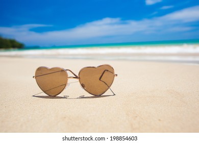 heart shaped sunglassses on the beach. travel concept