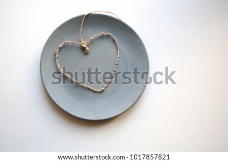 Heart shaped valentine made from flexible wire and beige string isolated on grey concrete plate