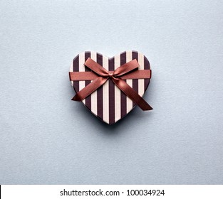 Heart shaped Valentines Day gift box on gray textured paper background.