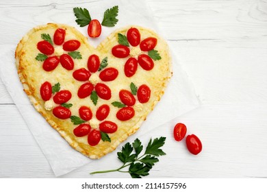 Heart shaped vegetarian Italian pizza with flower shaped tomatoes,cauliflowers and parleys on parchment paper with white wood background.Romantic art food idea for Valentine's day.Top view.Copy space - Shutterstock ID 2114157596