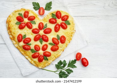 Heart shaped vegetarian Italian pizza with flower shaped tomatoes,cauliflowers and parleys on parchment paper with white wood background.Love concept for Valentine's day and Mother's day.Top view

 - Shutterstock ID 2147412199