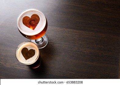 Heart Silhouettes In Two Glasses Of Fresh Beer On Pub Table, View From Above