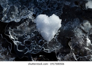 Heart of snow naturally formed by coincidence on the frozen icy surface of a small creek in Sauerland germany on a cold frosty day with low temperature. Symbol for love and emotions on Valentines day.