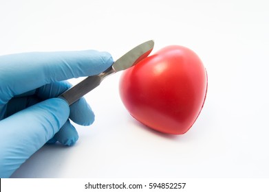 Heart Surgery Or Cardiac Surgery (cardiosurgery). Doctor Surgeon Holding Scalpel In Hand And Cut Red Heart Shape On White Background. Concept For Surgical Operations On Heart In Adults And Children