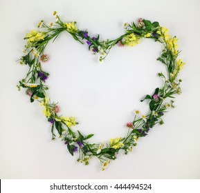 Heart symbol made of meadow flowers and leaves on white background. Flat lay, top view - Powered by Shutterstock