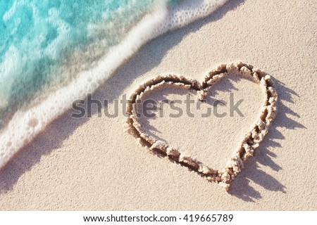 Heart Symbol On a Sand Of Beach With Soft Blue Wave On Background