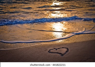 a heart waiting for you on the beach by the sea lit by the sunset