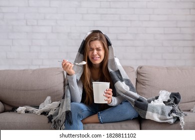 Heartbroken young woman eating ice cream from bucket while watching romantic movie on TV at home. Sad lady crying over breakup or relationship problems, feeling depressed and lonely