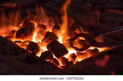 Hearth In The Forge. A Metal Tool Holds A Red-hot Piece Of Iron On Fire. Before  Start Forging