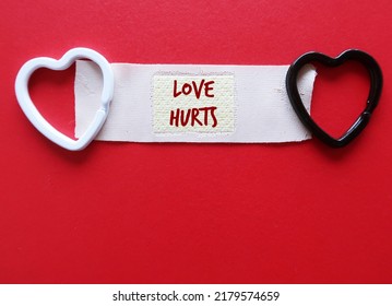 Hearts On Band Aid Plaster On Red Copy Space Background With Handwritten Text LOVE HURTS, Concept Of Healing A Broken Heart, Fix A Wounded Painful Heartbreak