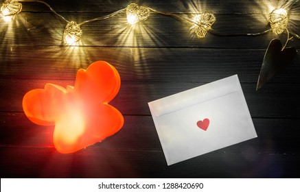 Hearts Shaped String Lights And White Envelope On Wooden Table Backdrop, Valentine Day Concept