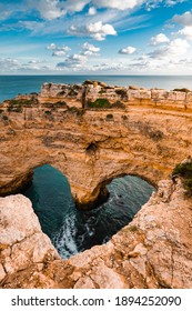 Heart-shaped cliffs on the shore of Atlantic ocean in Algarve, Portugal. Selective focus. Beautiful summer landscape.
