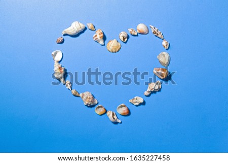 Heart-shaped composition, composed of various and deverse sea shells, on a blu plane.