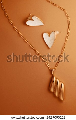 Heart-shaped earrings made of gold and enamel and a gold pendant on a necklace