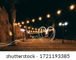 A heart-shaped light drawing on a long step on the steps in Jaffa. Perspective of lanterns and garlands with bulbs. Against the background of palm trees and yellow walls. Tourist place in Jaffa