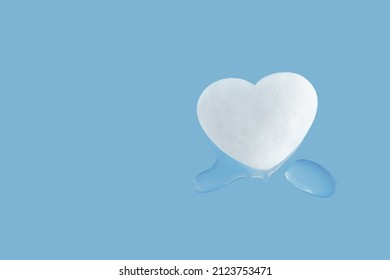 Heart-shaped Melting Snowball And Drops Of Water On Isolated Pastel Blue Background. Concept Of Love Or Forgiveness. Creative Valentine’s Day Greeting Card With Copy Space. Minimal Abstract Flat Lay.