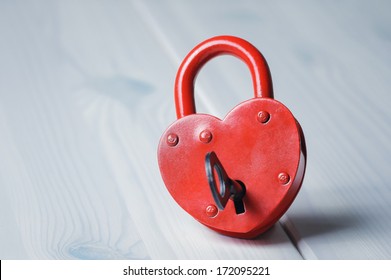 Heart-shaped padlock with key on wooden table