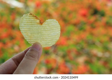 Heart-shaped potato chip in woman hand with colorful leaves in autumn background. Food and Valentine's day concept. - Powered by Shutterstock