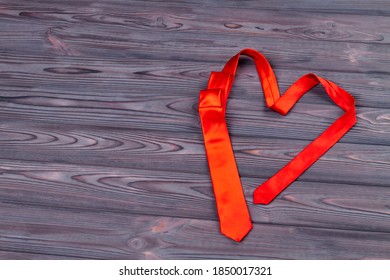 Heart-shaped red tie on wood. Top view love concept.