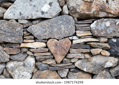 A Heart-shaped Stone Stuck In The Middle Of A Wall With Other Small And Large Stones