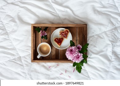 Heart-shaped Toast Bread With Jam, A Cup Of Coffee And Yellow Roses On A Wooden Serving Tray. White Duvet, Mothers Day, Top View.