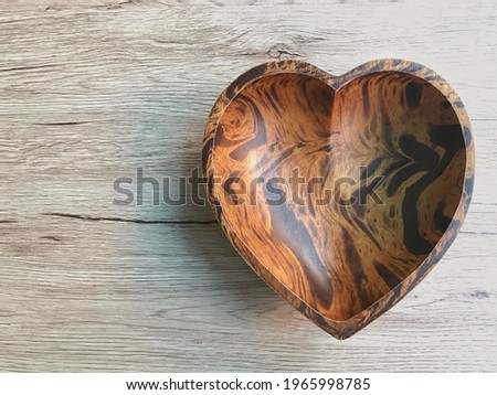 The heart-shaped wooden plate on the wooden table