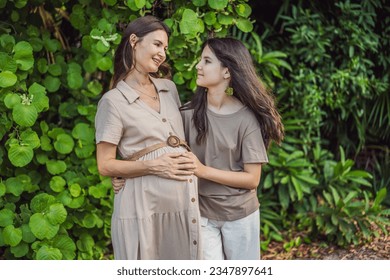 A heartwarming moment captured in the park as a pregnant woman after 40 shares a special bond with her teenage daughter, embracing the beauty of mother-daughter connection - Shutterstock ID 2347897641