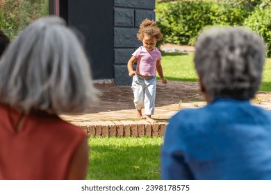 Heartwarming scene of loving grandparents gazing with affection as their young granddaughter plays, capturing a tender family moment outdoors. - Powered by Shutterstock