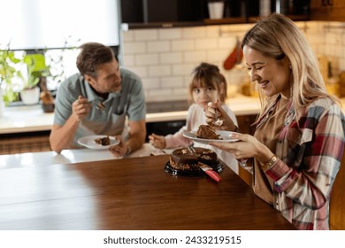 A heartwarming scene unfolds as a family relishes a mouthwatering chocolate cake together in the warmth of their sunlit kitchen, sharing smiles and creating memories - Powered by Shutterstock