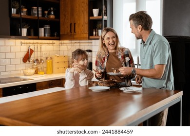 A heartwarming scene unfolds as a family relishes a mouthwatering chocolate cake together in the warmth of their sunlit kitchen, sharing smiles and creating memories - Powered by Shutterstock