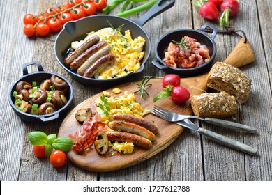 A hearty breakfast with scrambled eggs with bacon, Nuremberg sausages and fried mushrooms on a rustic wooden table