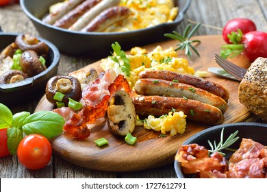 A hearty breakfast with scrambled eggs with bacon, Nuremberg sausages and fried mushrooms on a rustic wooden table