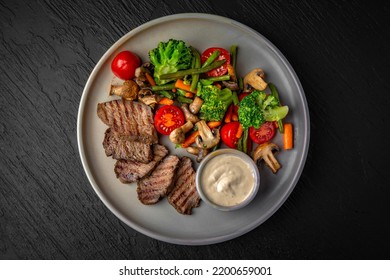 Hearty, Dietary Dish. Salad With Beef, Vegetables And Tuna Sauce In A Ceramic Plate On A Dark Textured Background. Restaurant Menu Isolated On Black